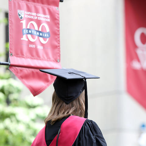 A Graduating Students looks at a Centennial Banner on Gutman Library