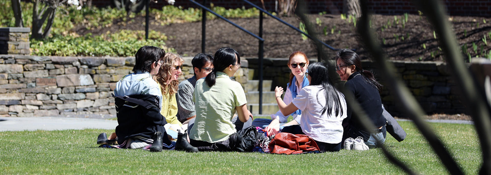 A group of students chat while sitting in a circle in the sunken garden